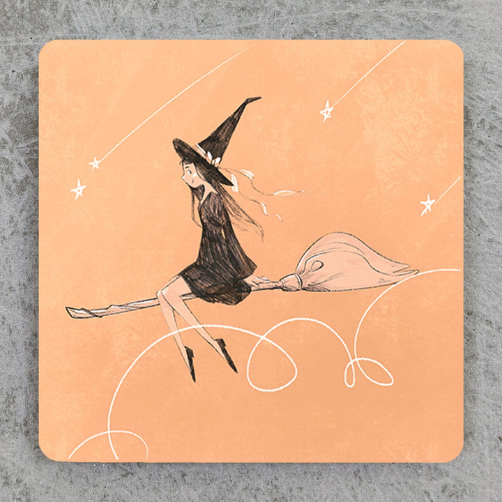 A image of an art print that depicts a witch girl wearing a black dress and a black hat flying on a broomstick. The girl is in front of orange background with motion doodles around her and shooting stars above. She is smiling and looks relaxed.